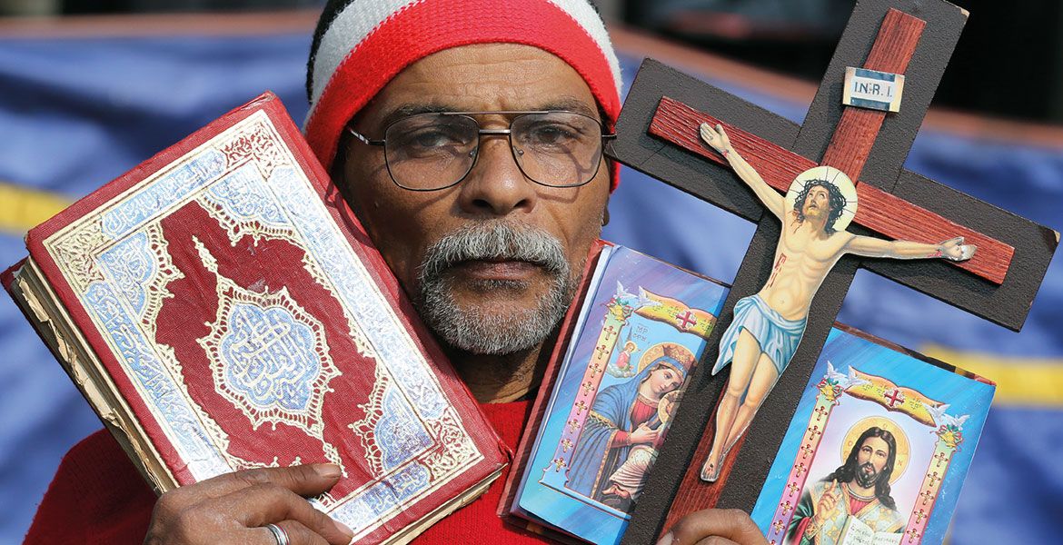 Ein Priester hält eine Bibel und ein Kreuz hoch - symbolisch für die Gefangenenseelsorge in Ägypten