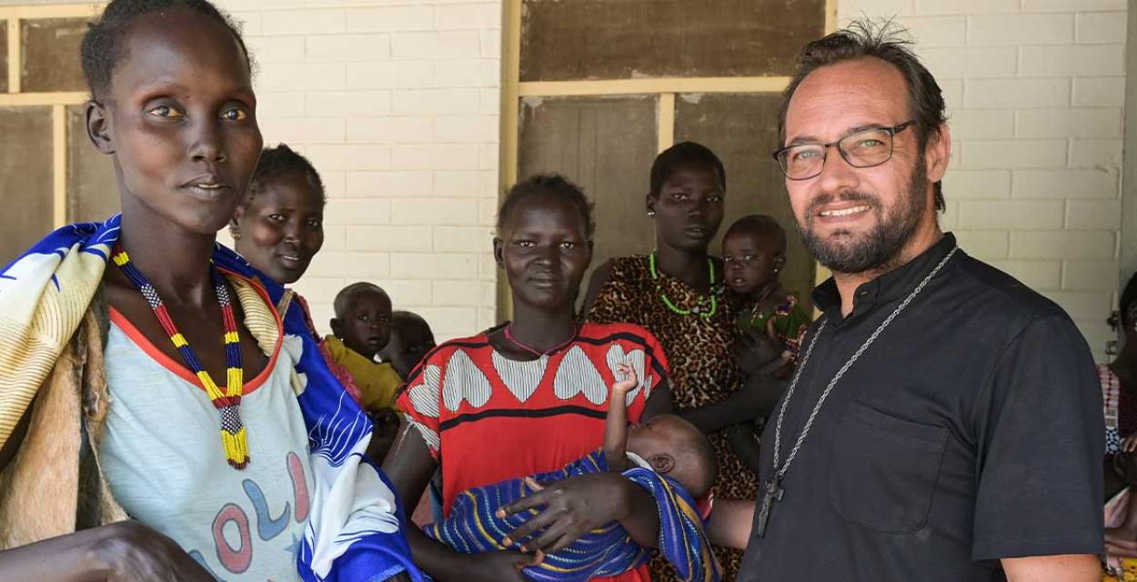 Zu sehen ist eine Gruppe von Menschen aus dem Südsudan, rechts vorne im Bild steht missio-Projektpartner Christian Carlassare, Bischof von Bentiu.