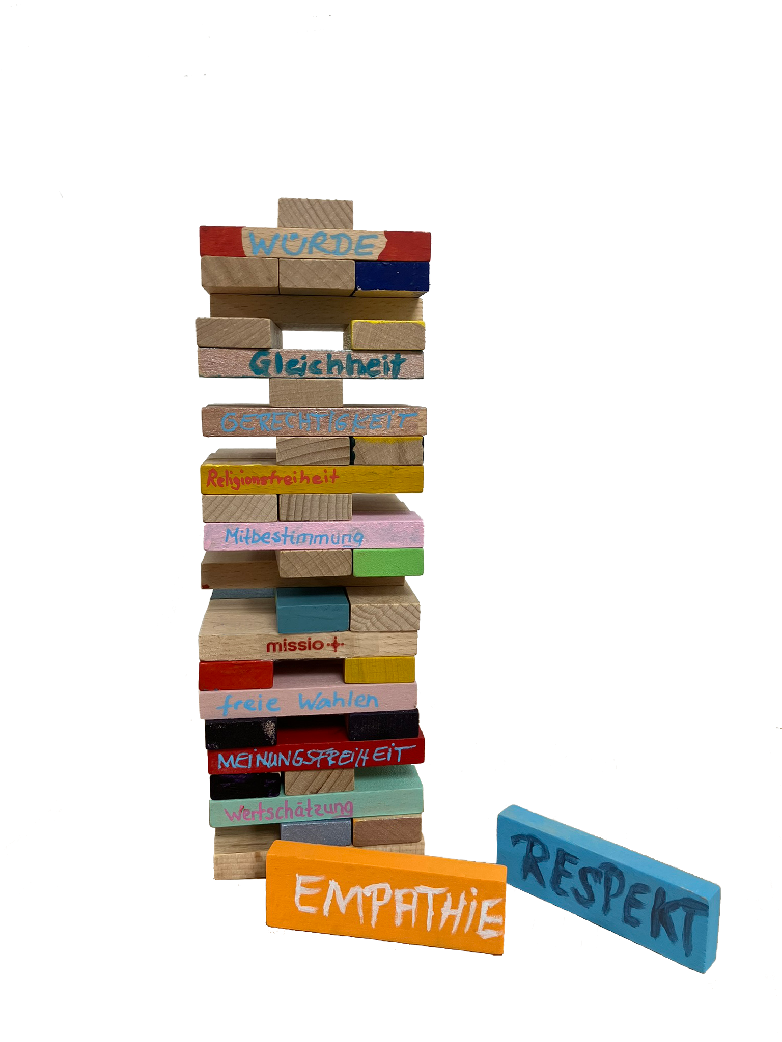 Ein bunt bemalter Holzstapelturm aus Jengasteinen ist beschriftet mit demokratischen Werten wie Respekt, Empathie, Meinungsfreiheit etc.