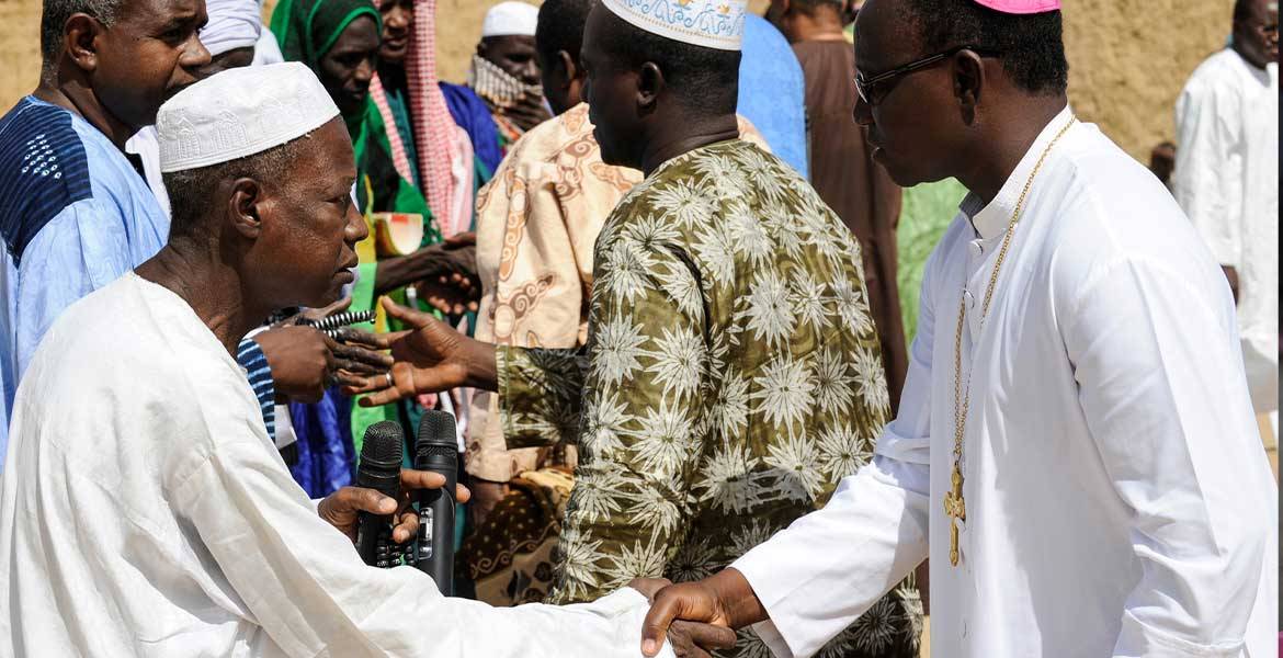 Ein Muslim, links im Bild, und ein katholischer Bischof, rechts im Bild, aus Burkina Faso reichen sich die Hand.