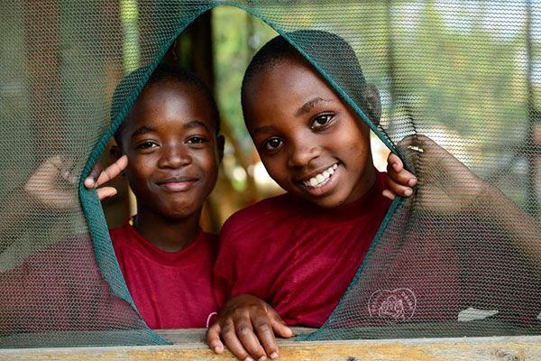 Kinder lachen durch einen Vorhang im Schutzzentrum Jipe Moyo in Tansania