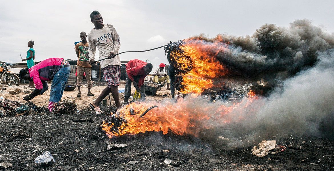 Menschen legen durch Feuer Metall auf einer Müllhalde frei