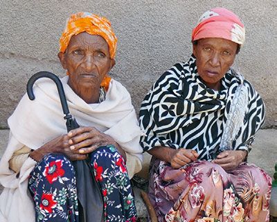 Zwei Seniorinnen sitzen vor einer Wand